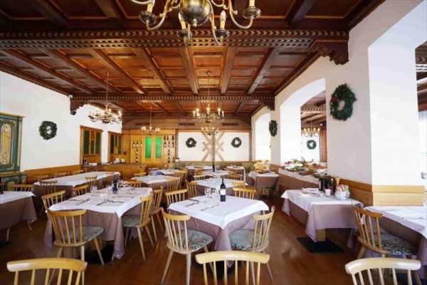 Restaurace s dřevěným stropem, kulatými stoly a vánoční výzdobou.