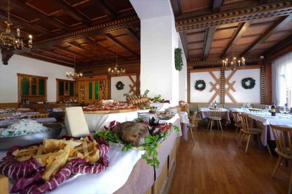 Stylová restaurace s dřevěným stropem a velkým bufetem plným jídel.