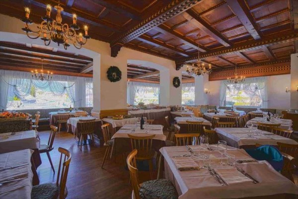 Restaurace s dřevěným stropem a prostřenými stoly.