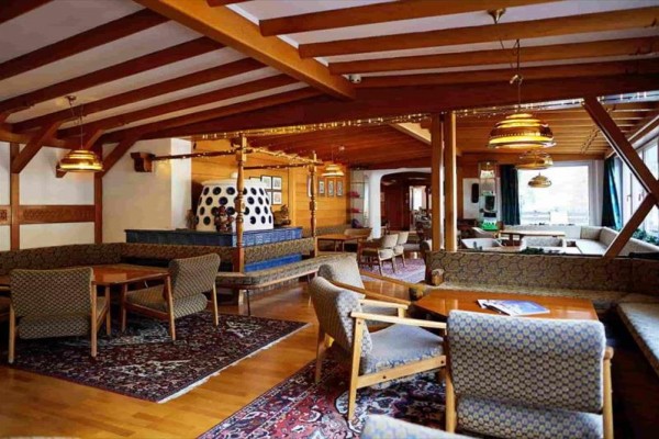Interiér rustikální restaurace s dřevěným stropem a ozdobným krbem.