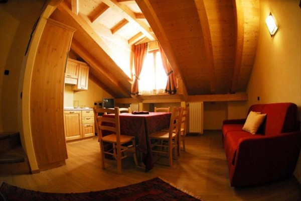 Podkrovní jídelna s dřevěným stropem a červenou pohovkou.