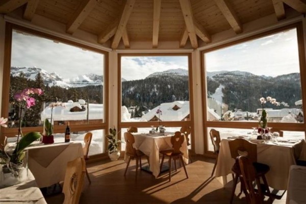 Restaurace s výhledem na zasněžené hory a lesy.
