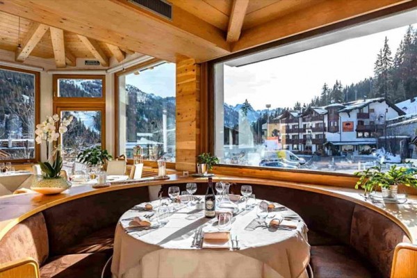 Luxusní restaurace s výhledem na zasněženou krajinu a horskou vesničku.