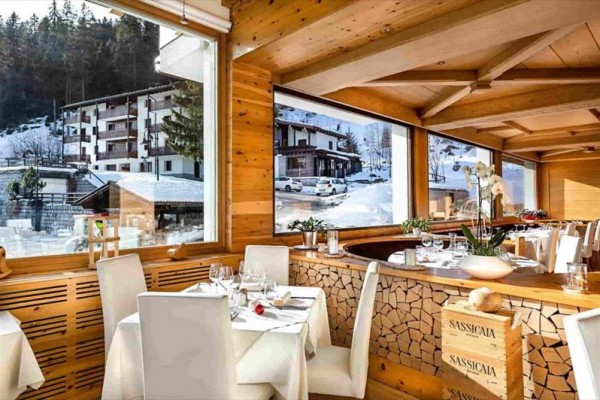Elegantní restaurace s dřevěným interiérem a velkými okny s výhledem na zasněžené hory.