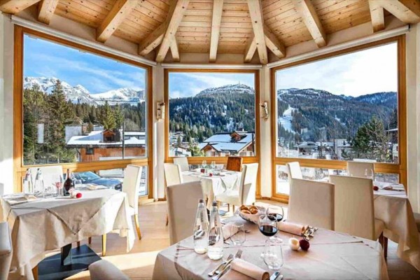 Restaurace s velkými okny nabízející výhled na zasněžené hory.