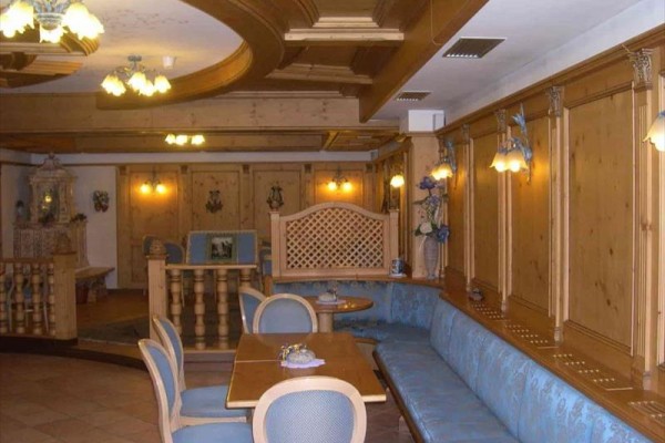 Interiér restaurace s dřevěným obložením, modrým čalouněním a stropními svítidly.