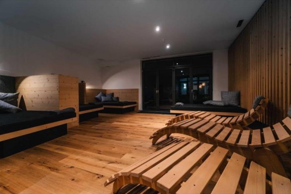 Relaxační místnost s dřevěnými lehátky a pohovkami.