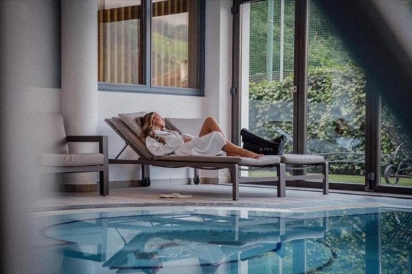 Žena relaxuje na lehátku u vnitřního bazénu.