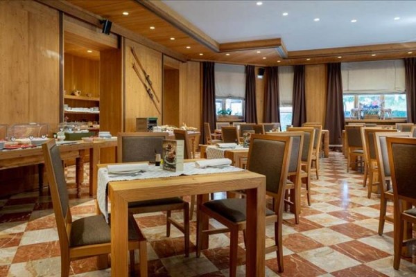 Prostorná restaurace s dřevěnými stoly a hnědými židlemi.