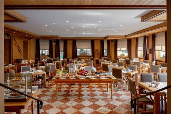 Elegantně zařízená restaurace s dřevěnými stoly a židlemi, prostřenými ke snídani.