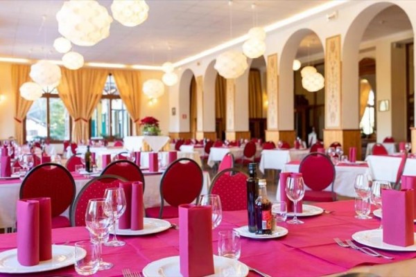 Elegantní restaurace s červeně prostřenými stoly a luxusním osvětlením.
