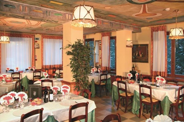 Elegatní restaurace s prostřenými stoly, látkovými ubrousky a lahvemi vína, v interiéru s ozdobným stropem a velkými okny.  