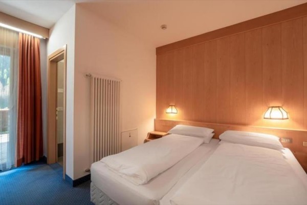 Pokoje v hotelu s dvěma jednolůžky vedle sebe, osvětlené lampičkami na zdi.
