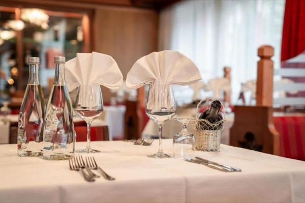 Elegantně prostřený stůl v restauraci s lahvemi vody a sklenicemi na víno.