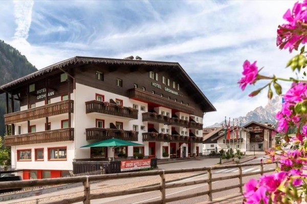 Hotel v alpském stylu s balkonem a květinami v popředí.