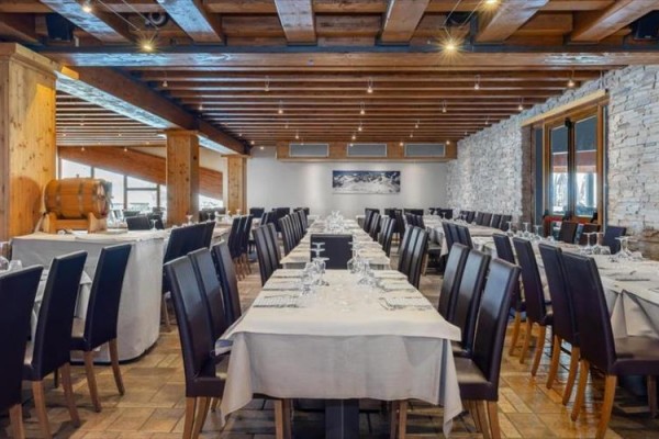 Stylová restaurace s dřevěnými prvky a prostřenými stoly.