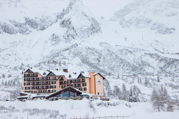 Hotel obklopený zasněženými horami a stromy v zimní krajině.