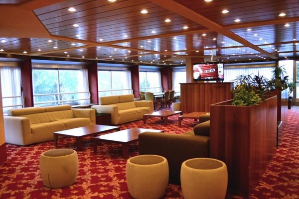 Elegantní lounge s pohovkami, konferenčními stolky a červeným kobercem.