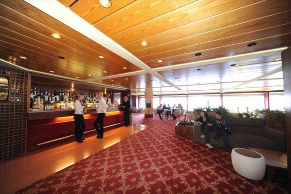 Luxusní hotelový bar s personálem a hosty relaxujícími na pohovkách.
