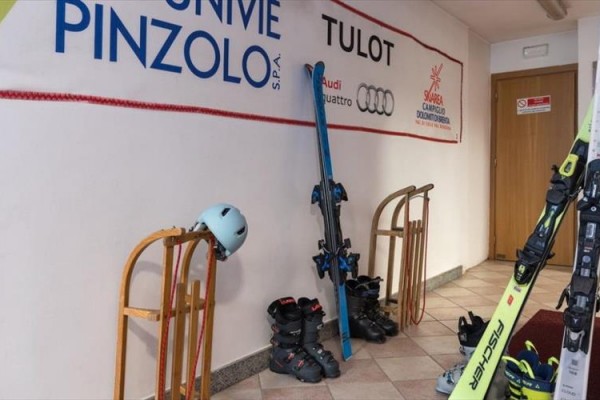 Lyžařská výbava se nachází u stěny s reklamními bannery.