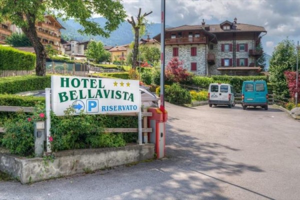 Hotel Bellavista se nachází vedle parkoviště s dvěma auty a obklopen zelení.