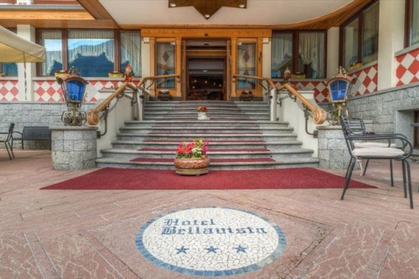 Vstup do hotelu s červeným kobercem a zdobeným schodištěm.