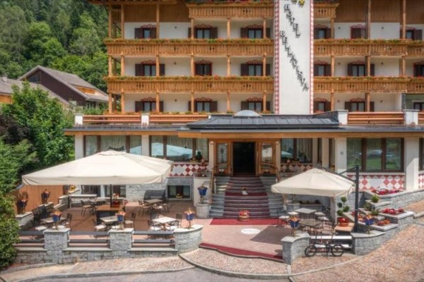 Vstup do horského hotelu s terasou a slunečníky.