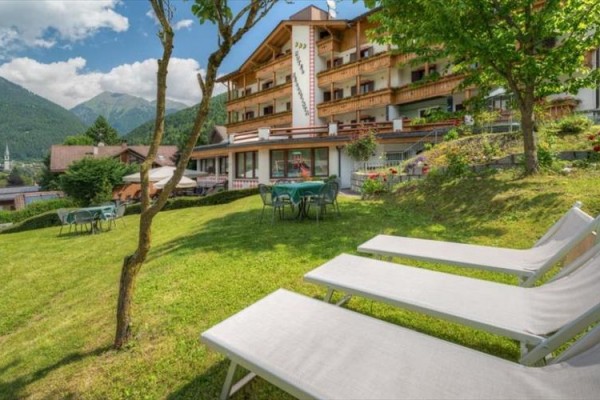 Hotel s lehátky a stoly na trávníku v horské krajině.