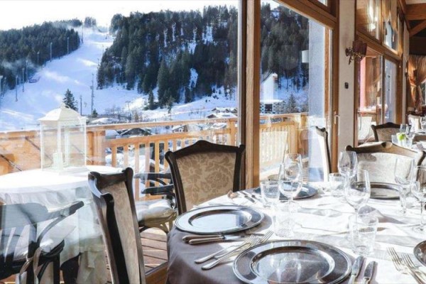 Restaurace s výhledem na zasněžené hory a lyžařskou sjezdovku.