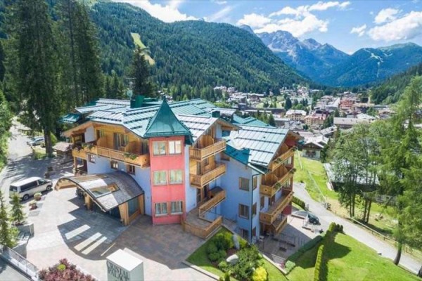 Hotel obklopený horami a lesy za slunečného dne.