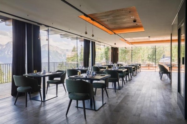 Moderní restaurace s velkými okny a výhledem na hory.