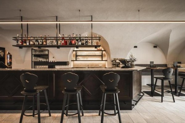 Stylový bar s vysokými židlemi a policemi s lahvemi alkoholu.