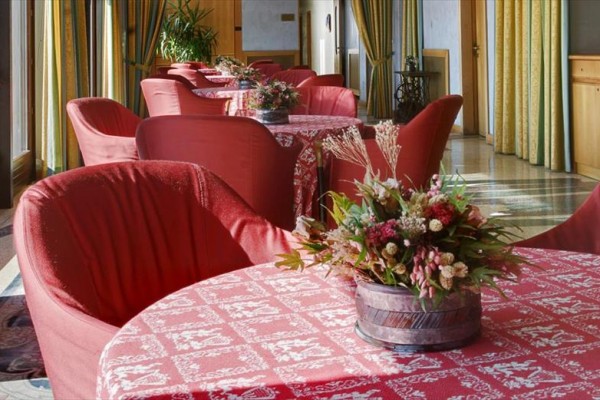 Restaurace s červenými ubrusy a květinovými aranžmá na stolech.