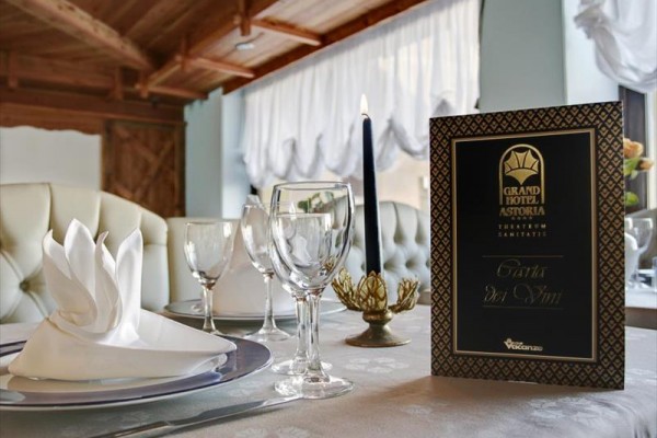 Elegantně prostřený stůl v hotelové restauraci s tácem, sklenicemi a svíčkou.  