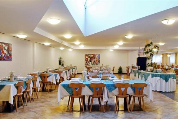 Elegantní restaurace s kruhovými stoly pokrytými modrými ubrusy.
