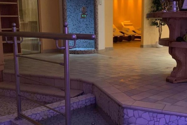 Relaxační zóna s lehátky a mozaikovou stěnou ve wellness centru.