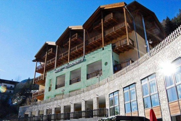 Hotel s terasami a dřevěnými balkony pod modrou oblohou.