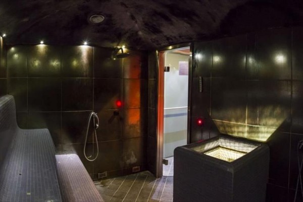Moderní parní sauna s lavicí, osvětlením a dveřmi do další místnosti.