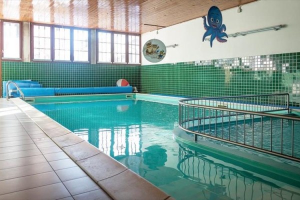 Vnitřní bazén s barevnými dlaždicemi a kresbou chobotnice na zdi.