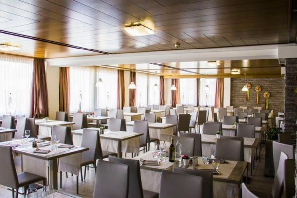 Restaurace s moderním interiérem a uspořádanými stoly s bílými ubrusy.  