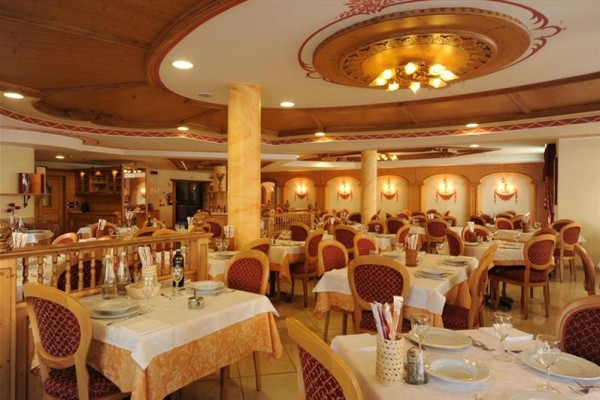 Vnitřek prostorné restaurace s dřevěnými prvky a červenými židlemi u stolů s bílými ubrusy.