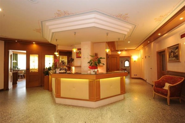 Recepce hotelu s dřevěným pultem a květinami.