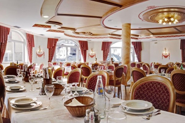 Stylová restaurace s elegantně prostřenými stoly a červenými židlemi.