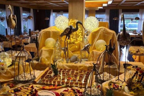 Luxusně ozdobený stůl s dezerty a dekoracemi zlatých tónů a sochami ptáků v elegantní jídelně.