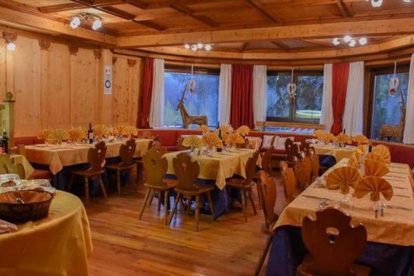 Restaurace s dřevěným interiérem, na stolech žluté ubrusy a složené ubrousky do tvaru vějířů.
