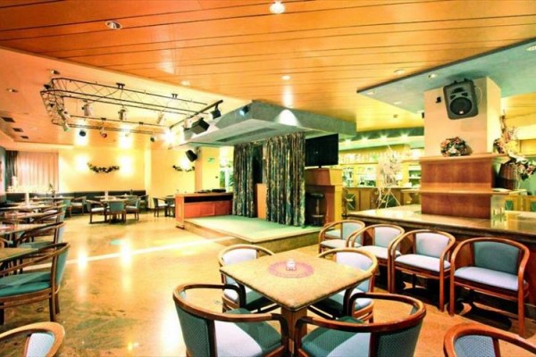 Restaurace s prázdnými stoly a židlemi, s pódiem a osvětlením.