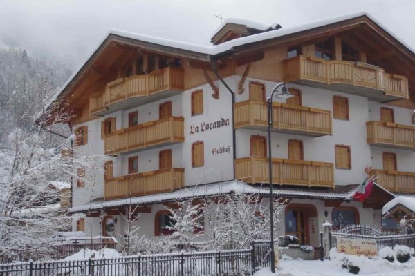 Horský hotel s dřevěnými balkony zasněžený v zimní krajině.