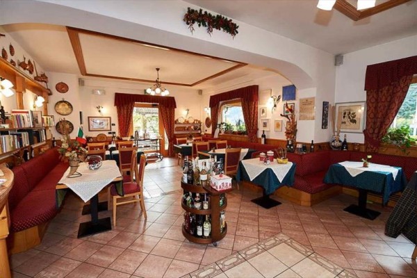 Interiér restaurace s dřevěným nábytkem, závěsy a dekoracemi.
