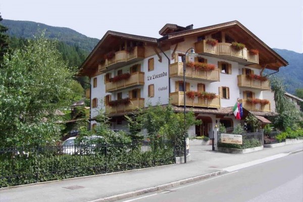 Třípatrový hotel s dřevěnými balkony a květinami na okrajích balkónů.