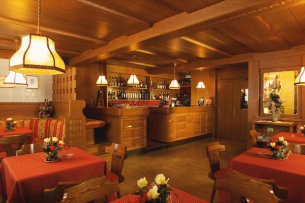 Interiér restaurace s dřevěným nábytkem a červenými ubrusy.